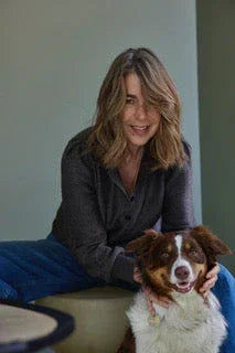 Larissa Giers seated in a serene, minimalist interior with her dog Tilda beside her, embodying calm and quiet presence.
