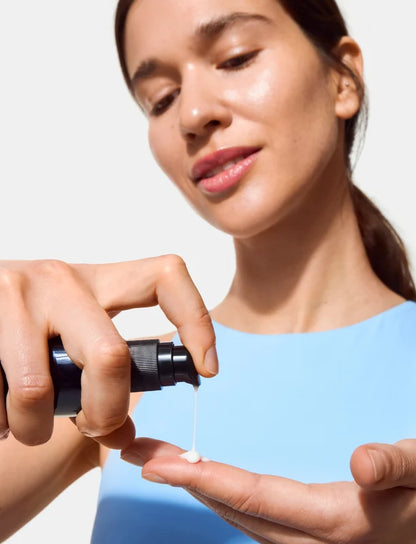Woman applying Oio Lab Intercellular Serum to her hand against a light background