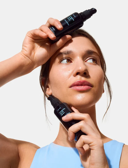 Woman applying Oio Lab Intercellular Serum to her face with a white background