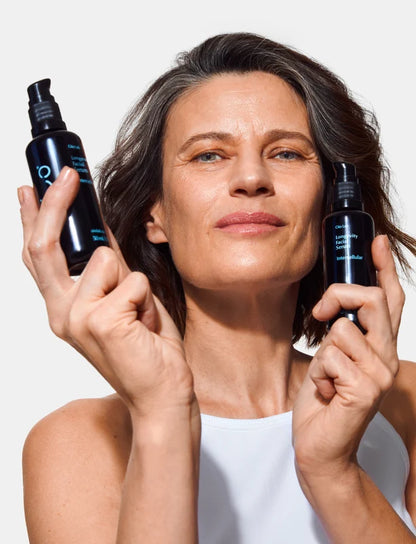 Woman holding two black bottles of Oio Lab Intercellular Serum with a white background
