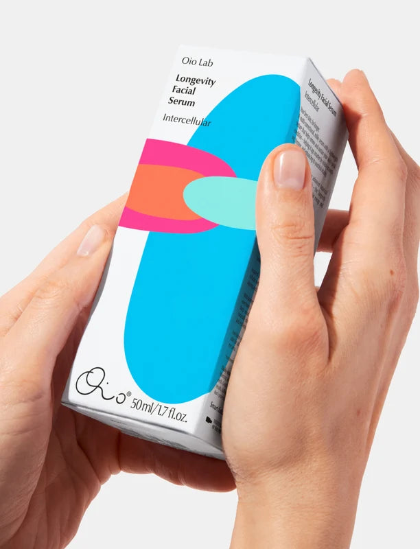 Oia Lab Longevity Facial Serum packaging held by hands against a white background