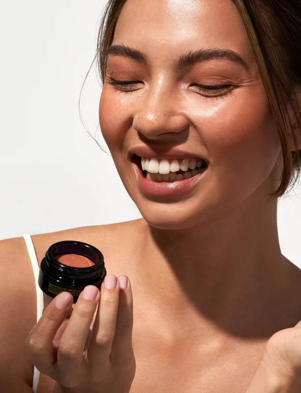 Model applying OIO Lab Melting Blush to cheeks for a natural healthy glow
