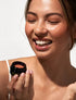 Model applying OIO Lab Melting Blush to cheeks for a natural healthy glow
