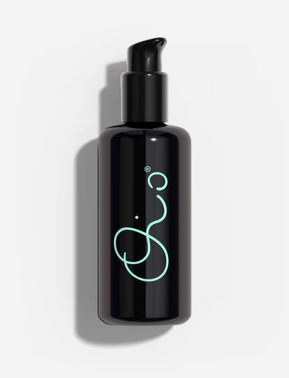 Oio Lab Omega Milk black pump bottle with a glowing mint green abstract logo, set against a clean white background with a soft shadow.