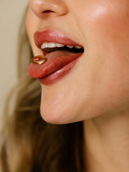 Close-up of Super Omega softgel capsule held on tongue – showing texture and size of the daily omega supplement